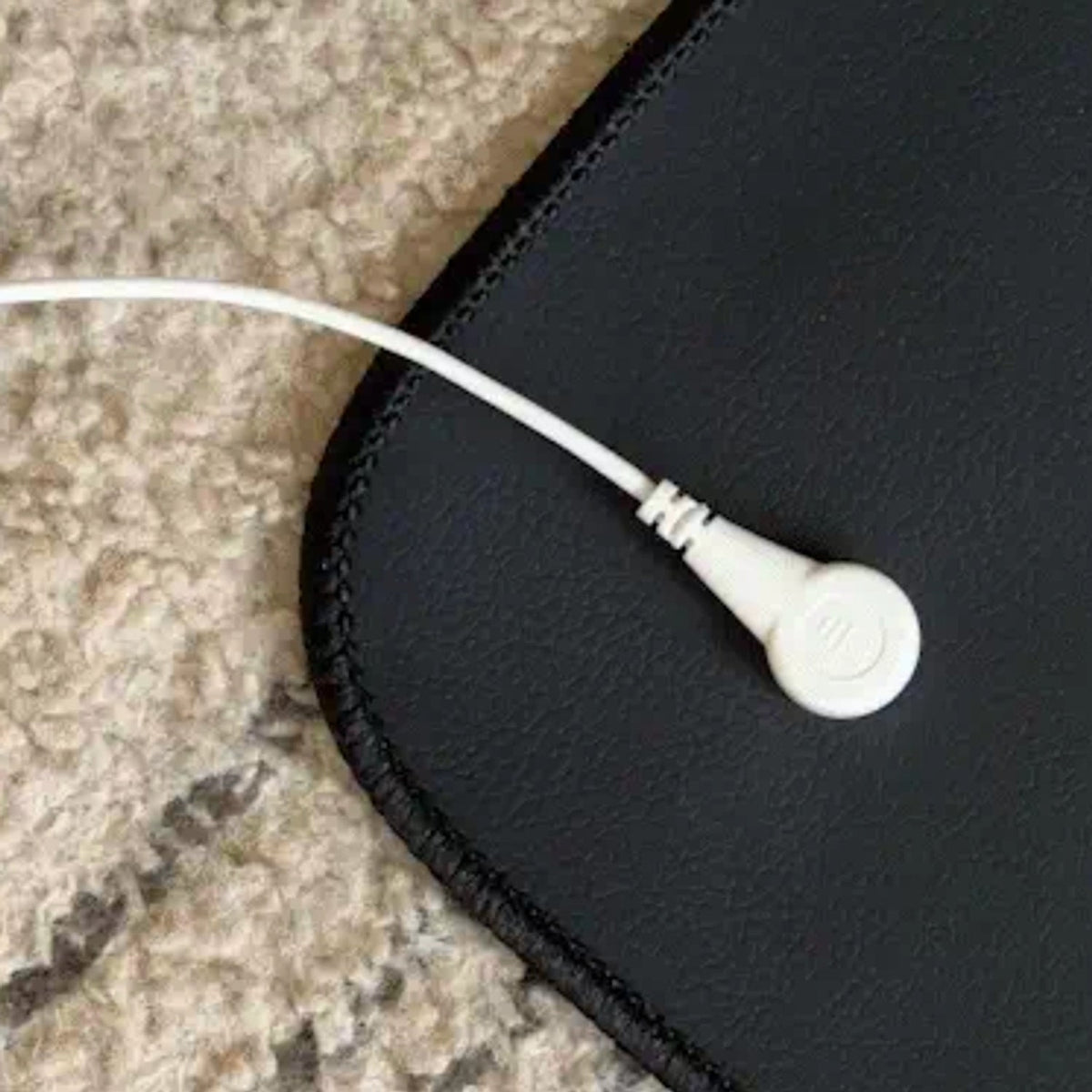 Close-up of the white snap connector and cable on the corner of the grounding mat